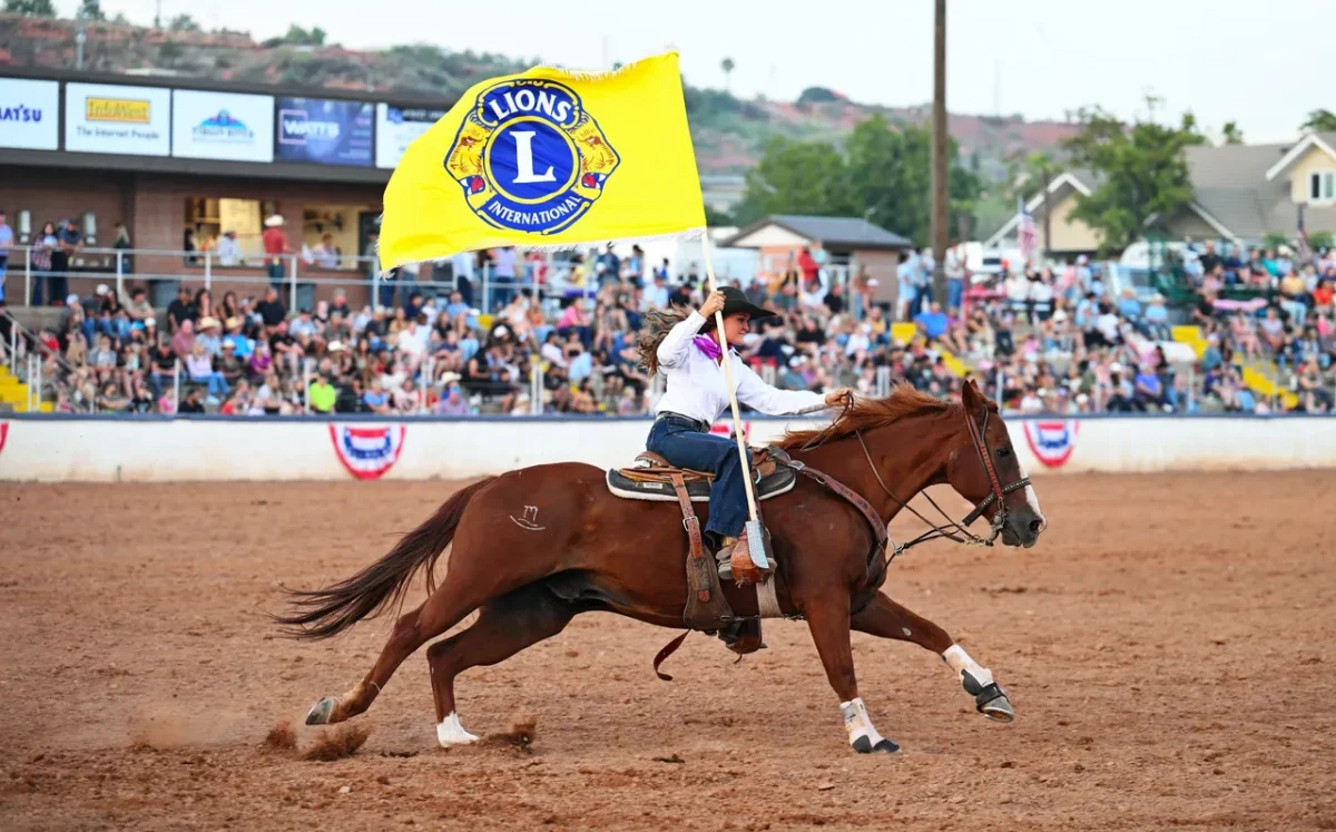 Dixie Round Up Rodea. Femal rider on a hourse with Lion's Club International Flag. 