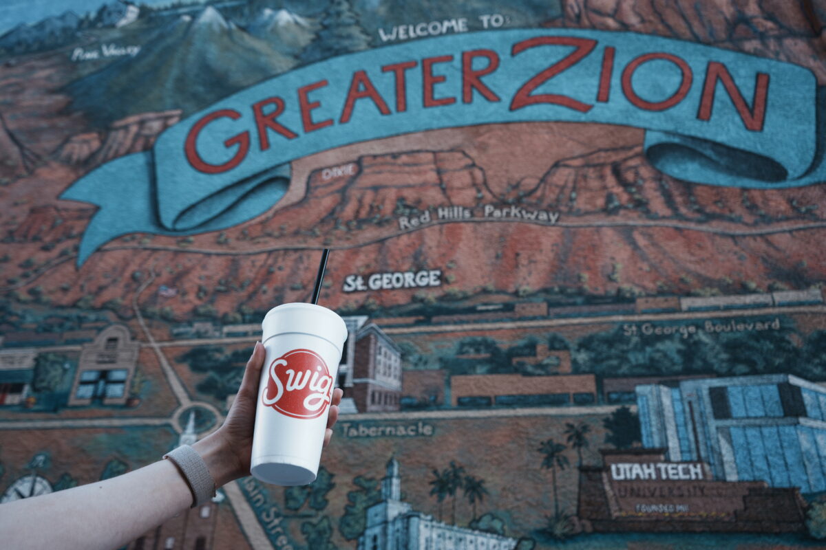 Swig cup held up in front of a mural of the Greater Zion map in Downtown St. George, Utah. 